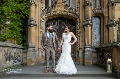 Bride and groom standing outside on the steps of Carlton Towers, holding hands and looking at each other.