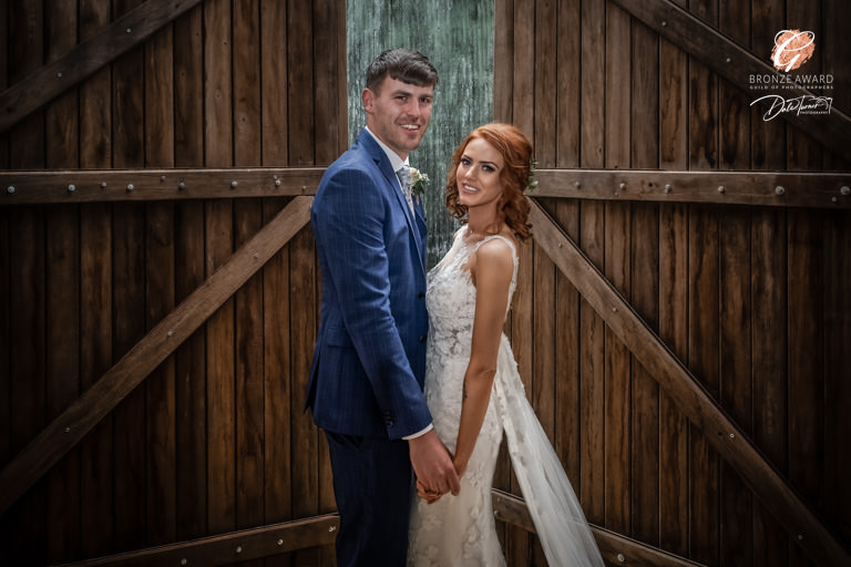Award winning image of bride and groom in front of large wooden doors at The Yorkshire Barns.