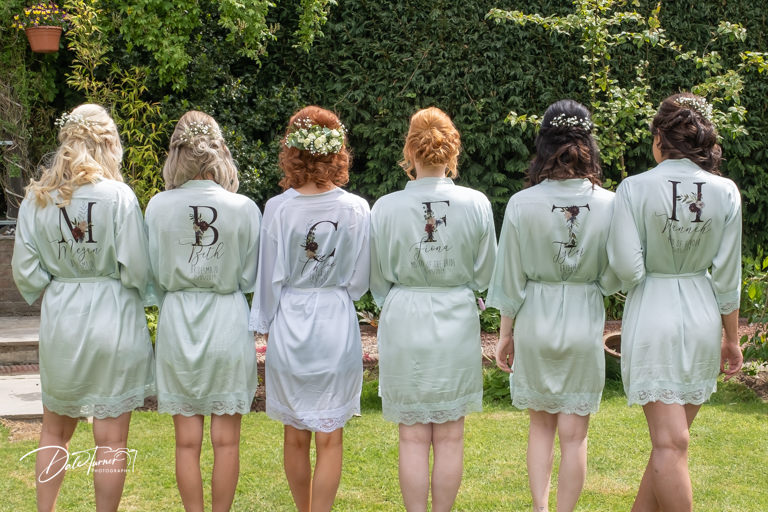 Bride and bridesmaids from behind showing off their personalised dressing gowns.