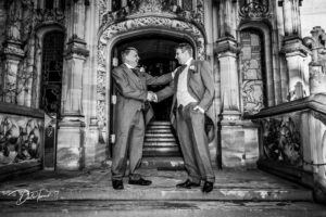 A groom and his dad shaking hands just before the wedding ceremony, outside of the main entrance at Carlton Towers.