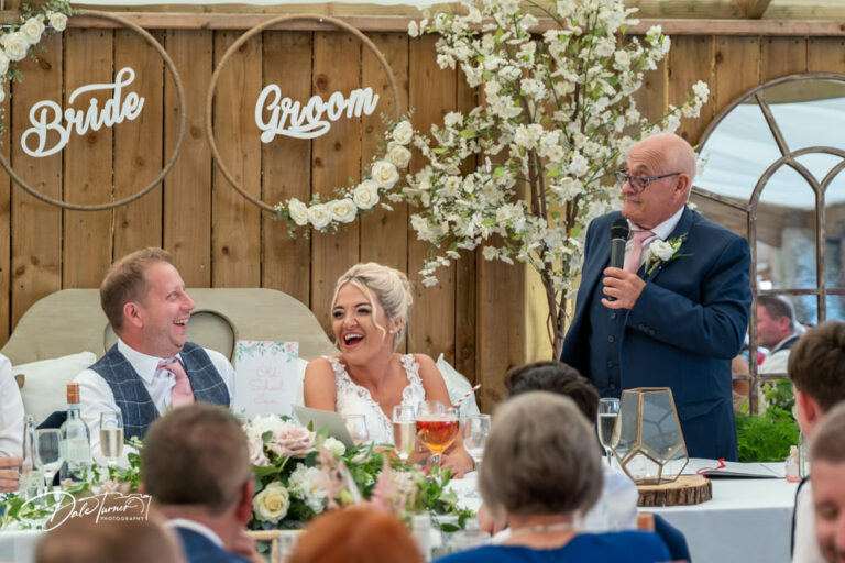 Father of the bride delivering his speech as the bride and groom laugh. At Loversall Farm, Tickhill.