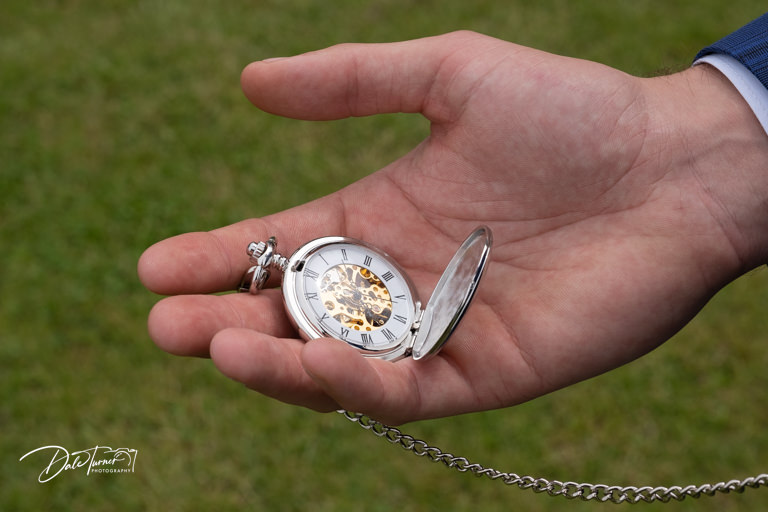 Close up of a pocket watch in the grooms hand.