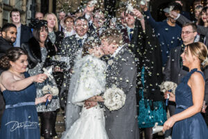 Bride and groom kissing while they are showered in confetti, at Carlton Towers.