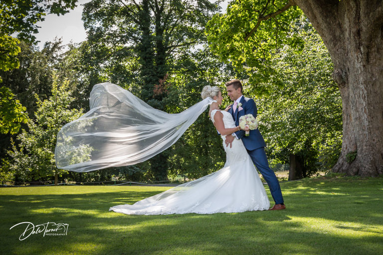 Bride and groom with huge flowing veil in the grounds of Hazlewood Castle.