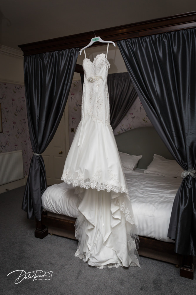 Wedding dress hung on a four poster bed.