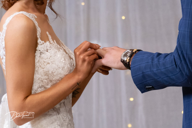 Close up of a bride placing a wedding ring on the groom.