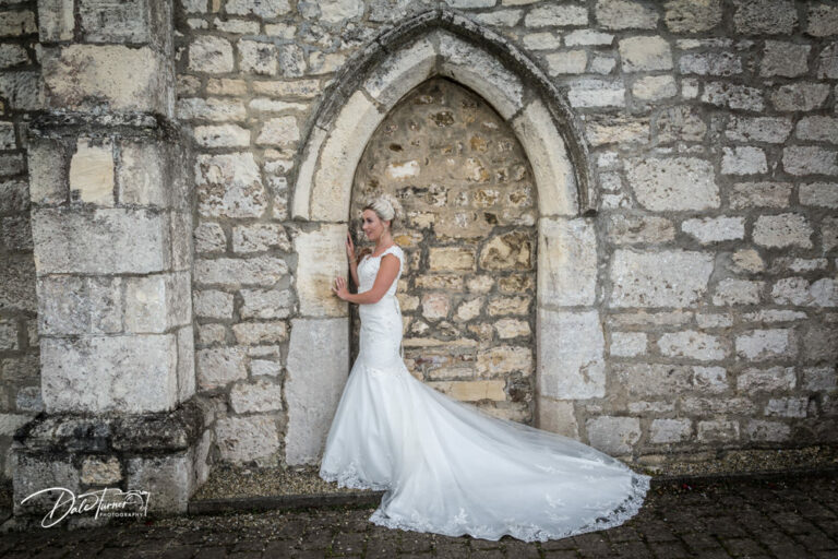 Bride leaning on a stone arch at Hazlewood Castle.