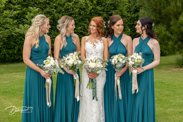 Bride and bridesmaids lined up and laughing with each other.