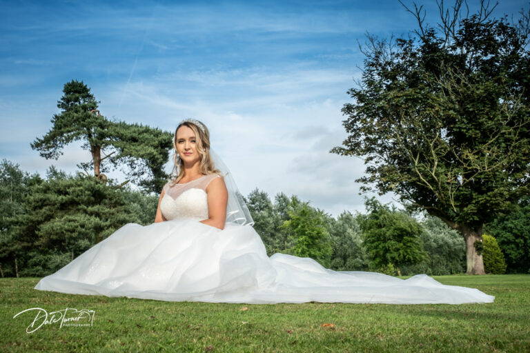 Bride sat on the grass in the grounds of Cave Castle.
