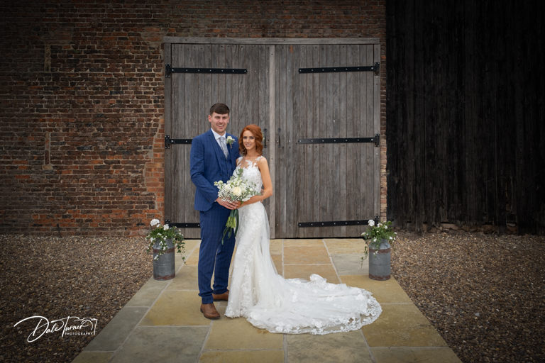 Bride and groom at The Yorkshire Barns in front of some large wooden doors.