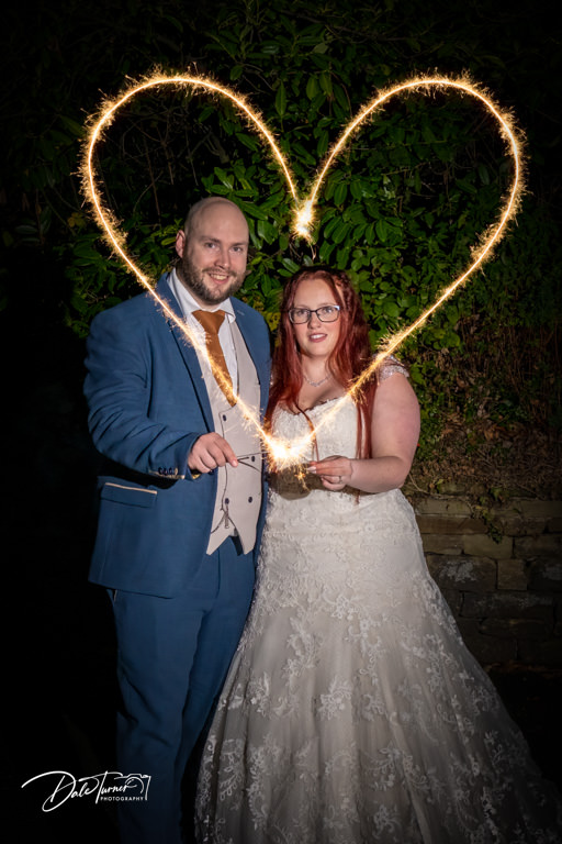 Bride and groom making a heart shape with sparklers, at Whitley Hall.
