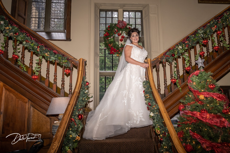 Bride on the staircase inside Whitley Hall with Christmas decorations.