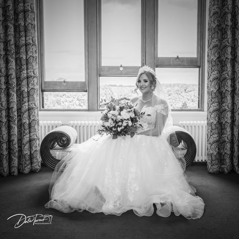 Bride sitting on a sofa in the bridal suite of Allerton Castle.