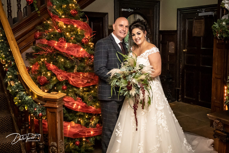 Bride and groom next to a Christmas tree at Whitley Hall.