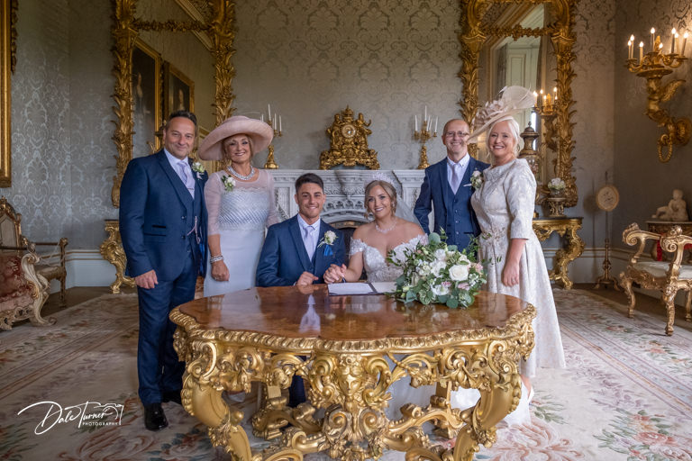 Bride, groom and parents signing the wedding register, at Allerton Castle.