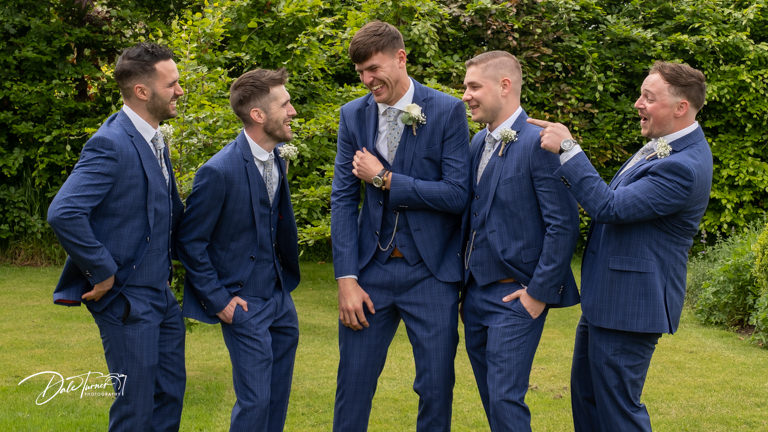 Groom and groomsmen laughing together.
