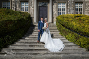 Bride and groom standing on the steps outside Hazlewood Castle.