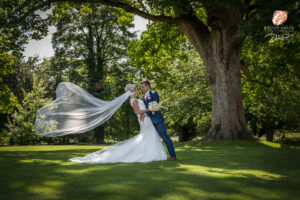 Award winning photograph of a bride and groom with a cathedral length veil in the grounds of Hazlewood Castle.