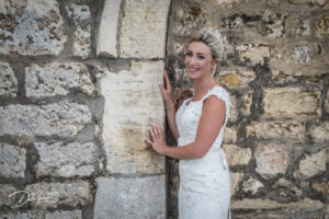 Bride holding onto a stonework wall, at Hazlewood Castle.