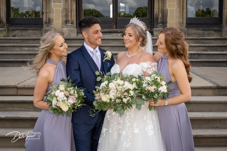 Bride, groom and two bridesmaids laughing together.