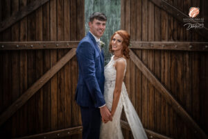 Award winning photograph of a bride and groom posing in front of some large barn doors.