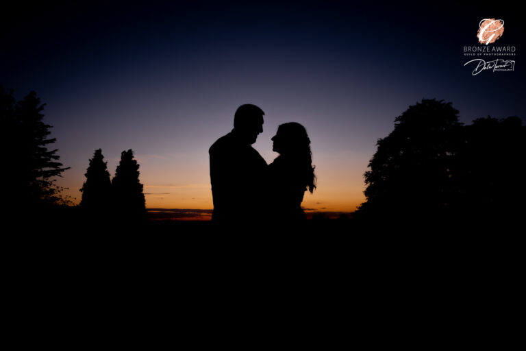 Bride and groom in silhouette against a sunset.
