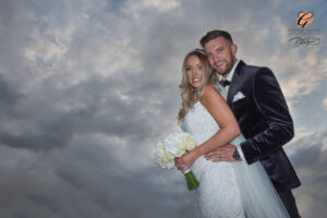 Award winning photograph of a bride and groom hugging with dark grey storm clouds, at Saltmarshe Hall.