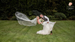 Award winning photograph of a bride and groom leaning back while the cathedral length veil flows behind the bride. In the grounds of Carlton Towers.