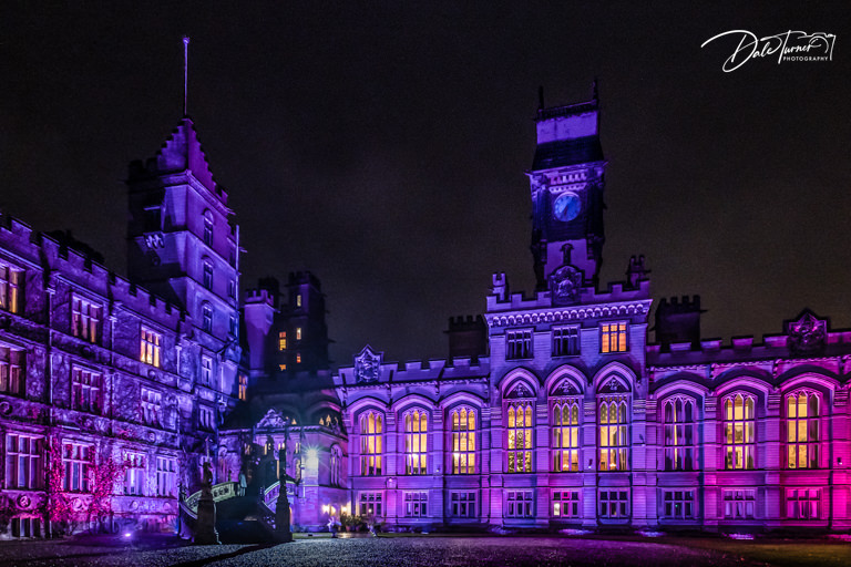 Illuminated historic building at night, purple lighting, Victorian architecture.