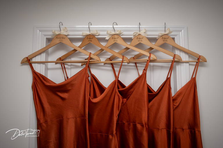 Bridesmaid dresses hanging on personalised hangers.