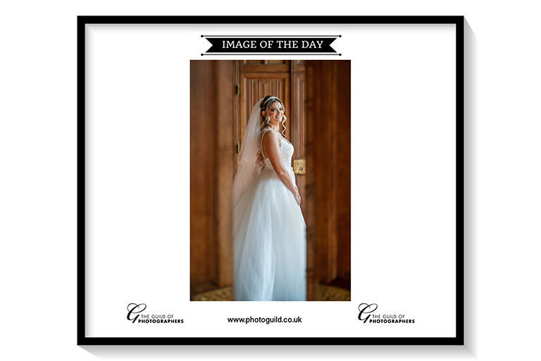 Bride in white dress standing by wooden door.
