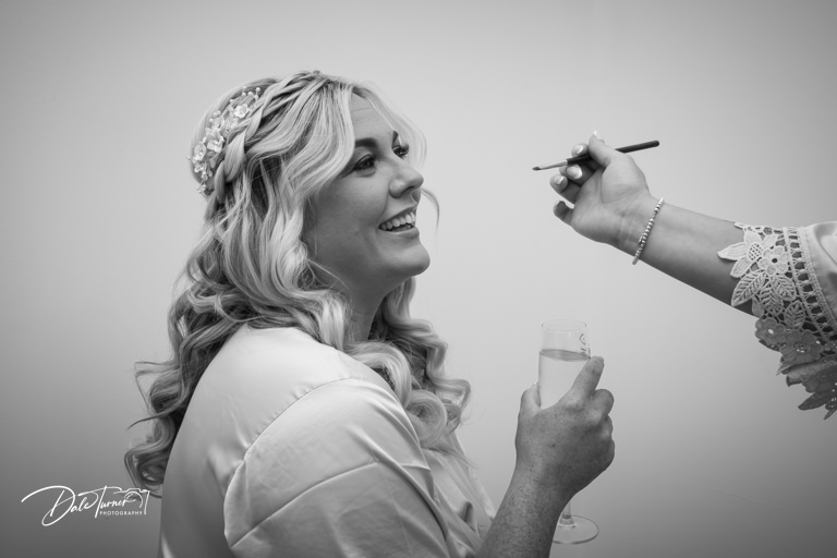 Bride getting makeup done, black and white photo.