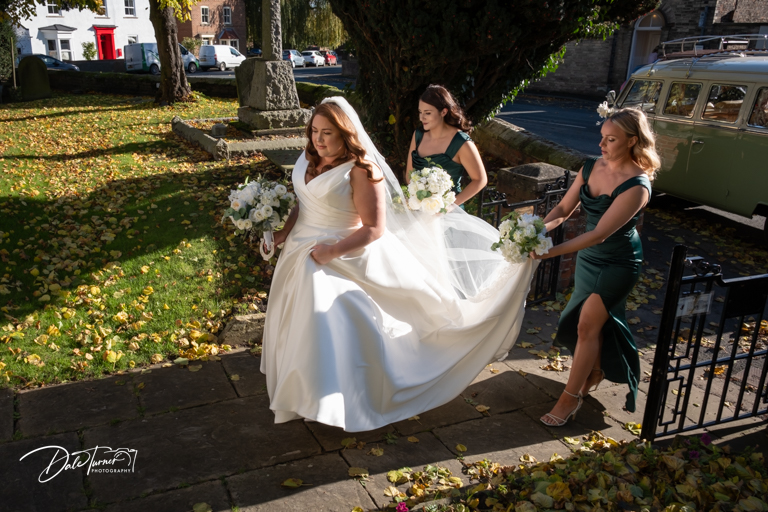 Bride and bridesmaids walking outdoors on sunny day.