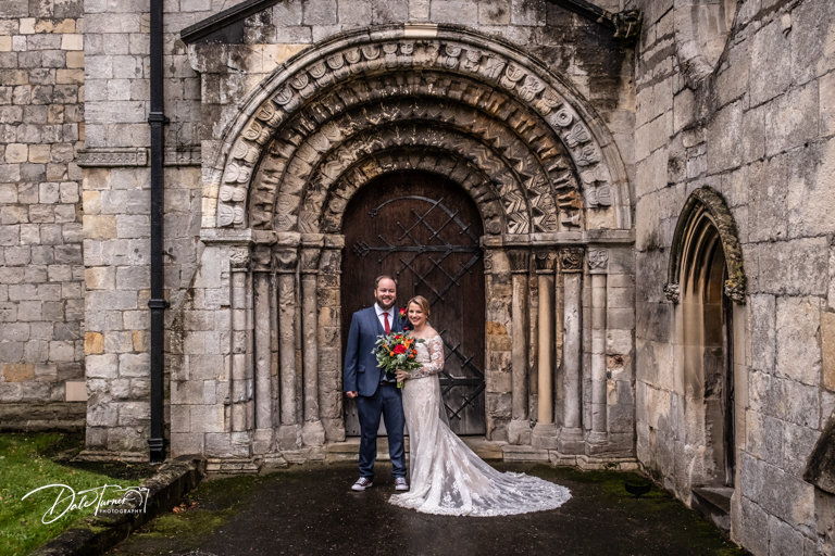 Couple posing in the doorway of St. Helen's church, Stillingfleet, after the wedding.