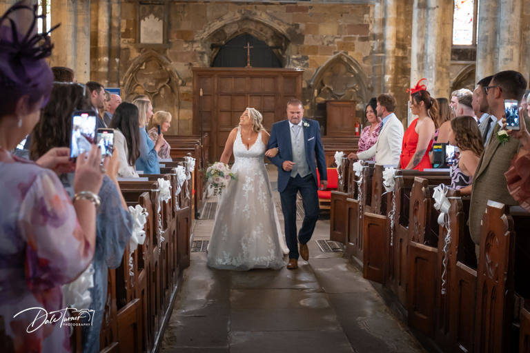 Bride walking down aisle with father at Howden Minster.