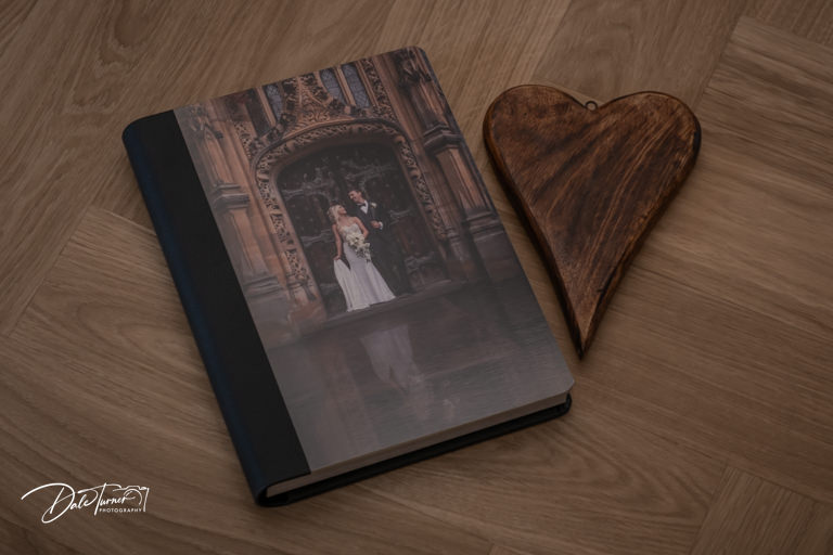 Wedding photo album and wooden heart on floor.