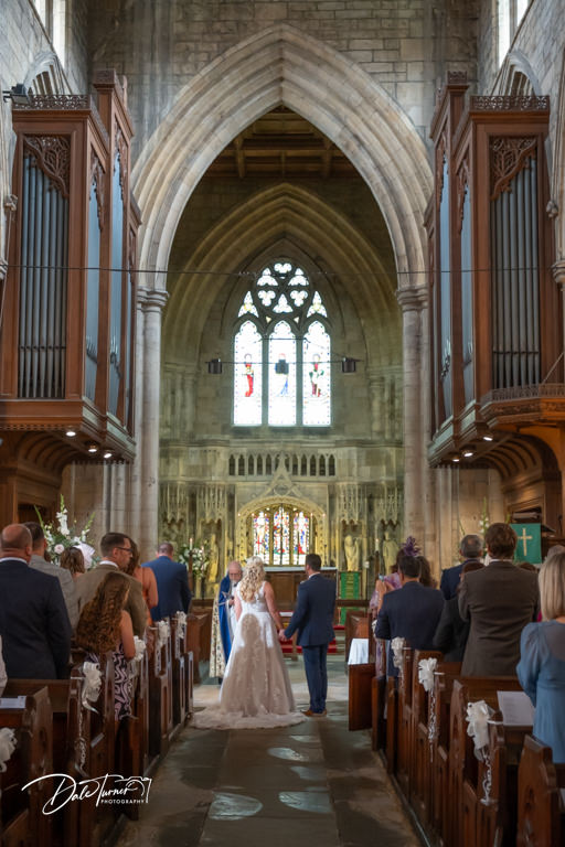 Bride and groom holding hands during wedding ceremony at Howden Minster.