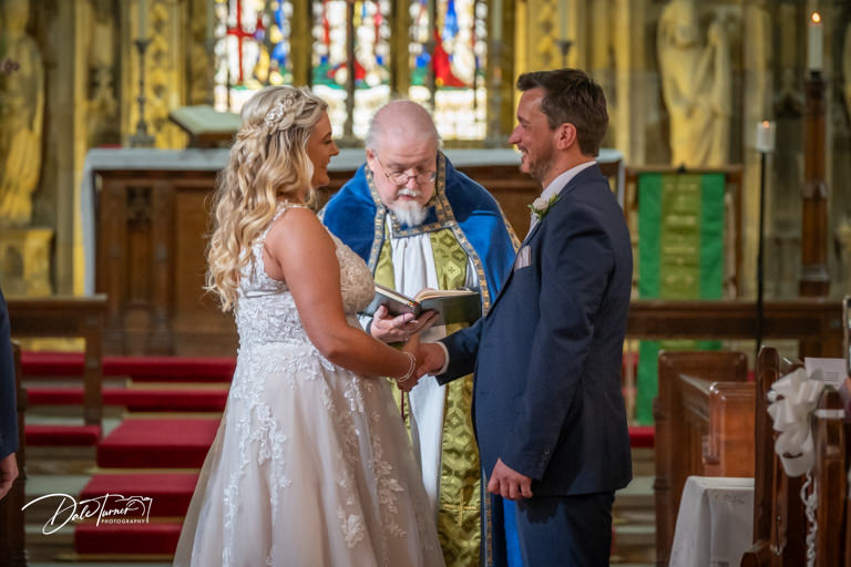 Bride and groom exchanging vows with officiant in Howden Minster.