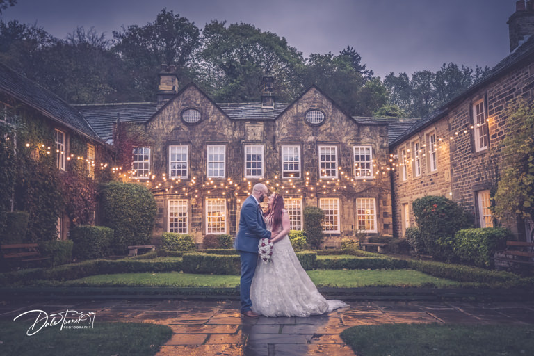 Bride and groom embracing with fairy lights in the background at twilight at Whitley Hall.