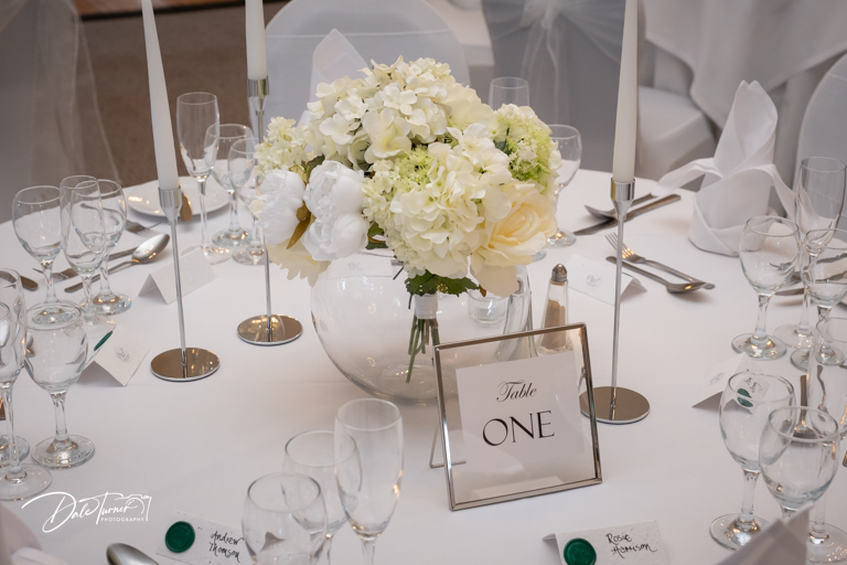 Elegant wedding table setting with white floral centerpiece.