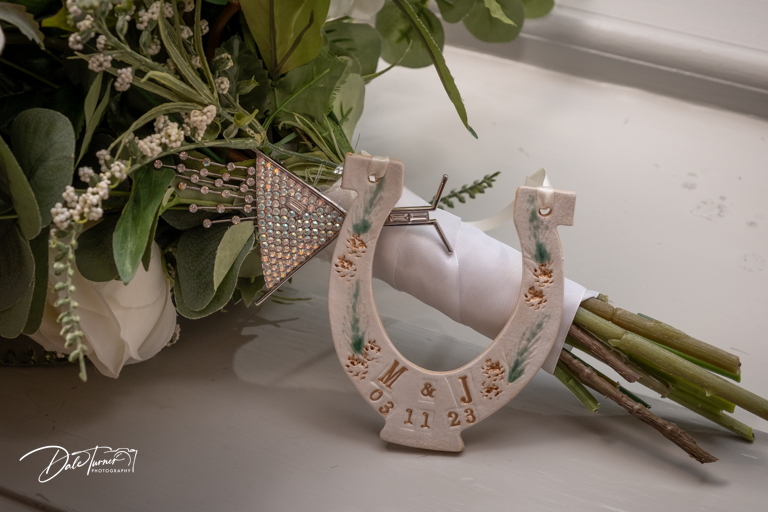 Horseshoe and bouquet at wedding with initials and date.