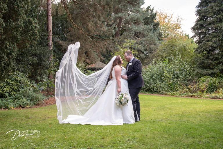 Bride and groom with veil in garden wedding.