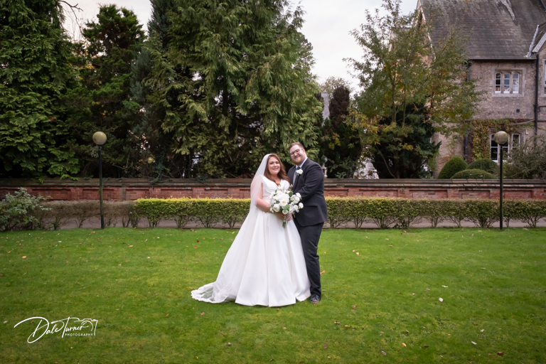 Wedding couple smiling outdoors at a historic manor venue.