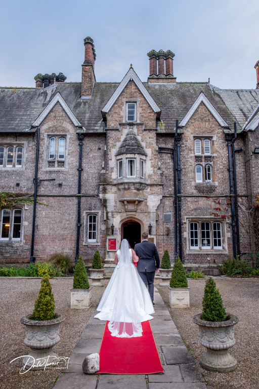 Bride and groom entering historic manor house wedding venue.