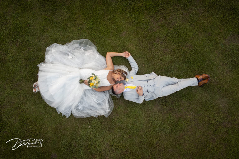 Bride and groom lying on grass, aerial view taken with a drone.