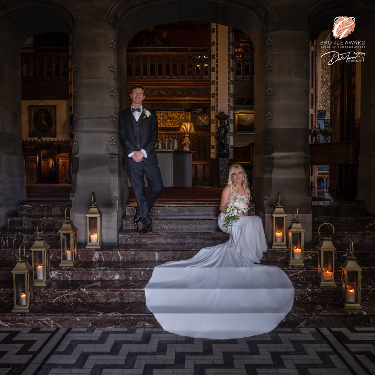 Elegant wedding couple in historic venue staircase.
