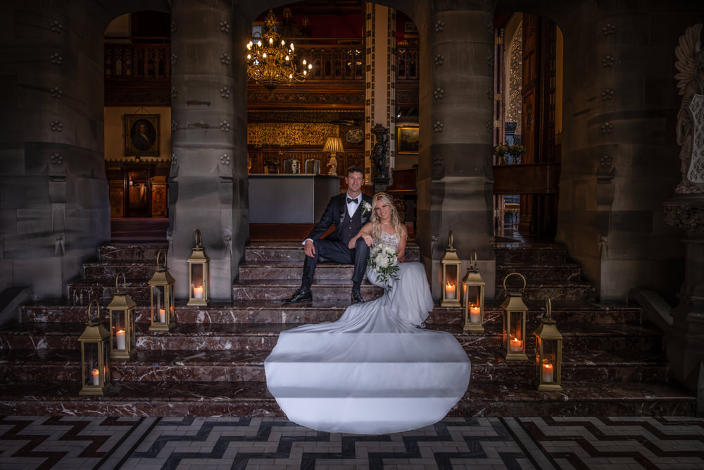 Couple posing on ornate staircase in candlelit setting
