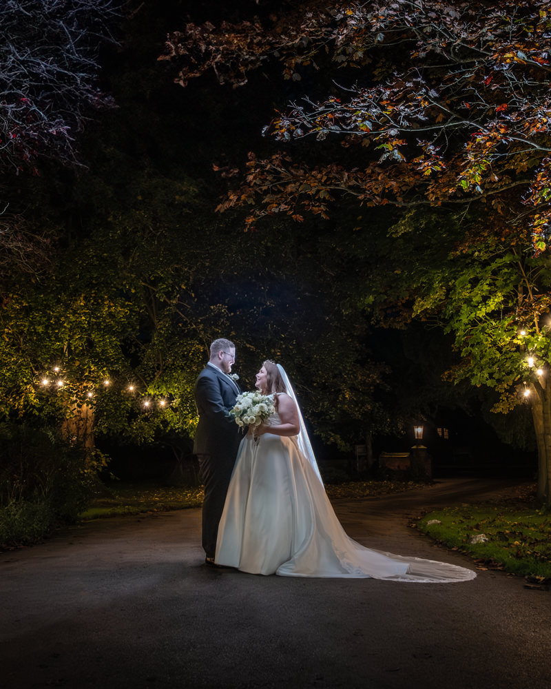 Nighttime wedding portrait with illuminated tree canopy