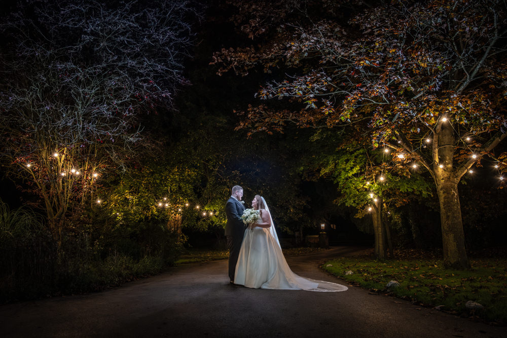 Wedding couple under twinkling lights in evening setting
