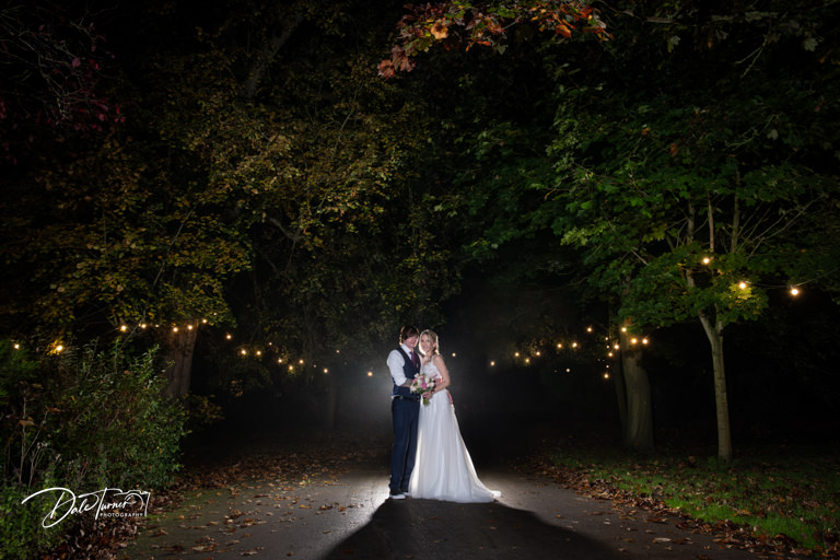 Couple in wedding attire under lights at nighttime at The Parsonage